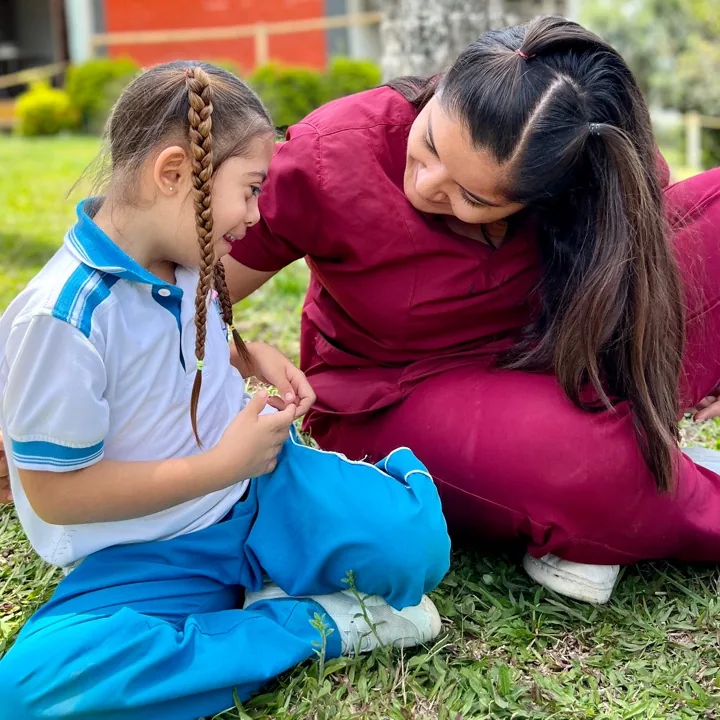 Maestra acompañando de cerca a una niña de preescolar
